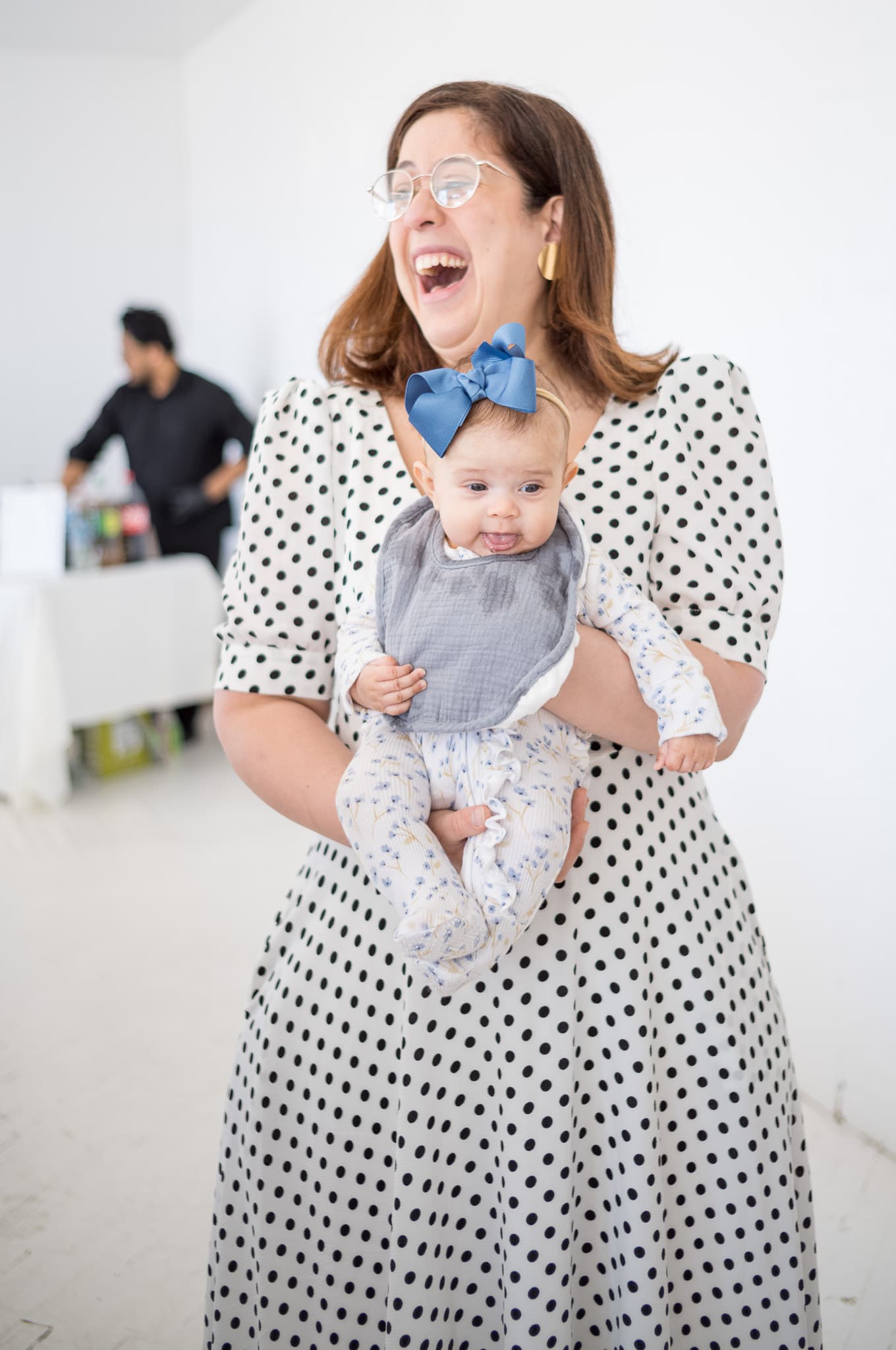 A guest laughing while holding a little boy at the celebration