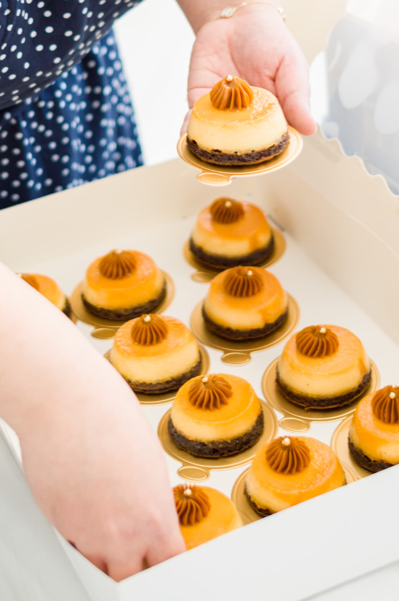 A box of caramel-topped petit fours being arranged for the dessert display