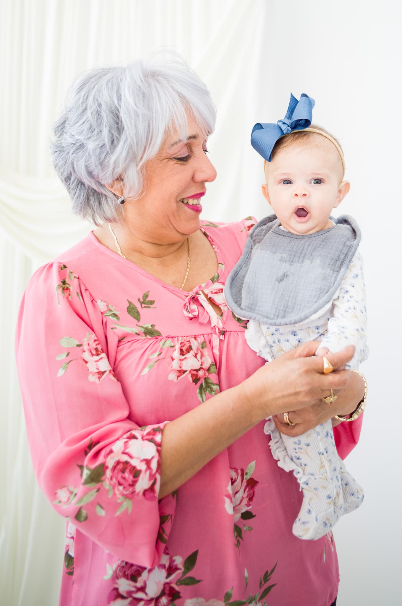 A grandmother smiling at the baby wearing a blue bow headband