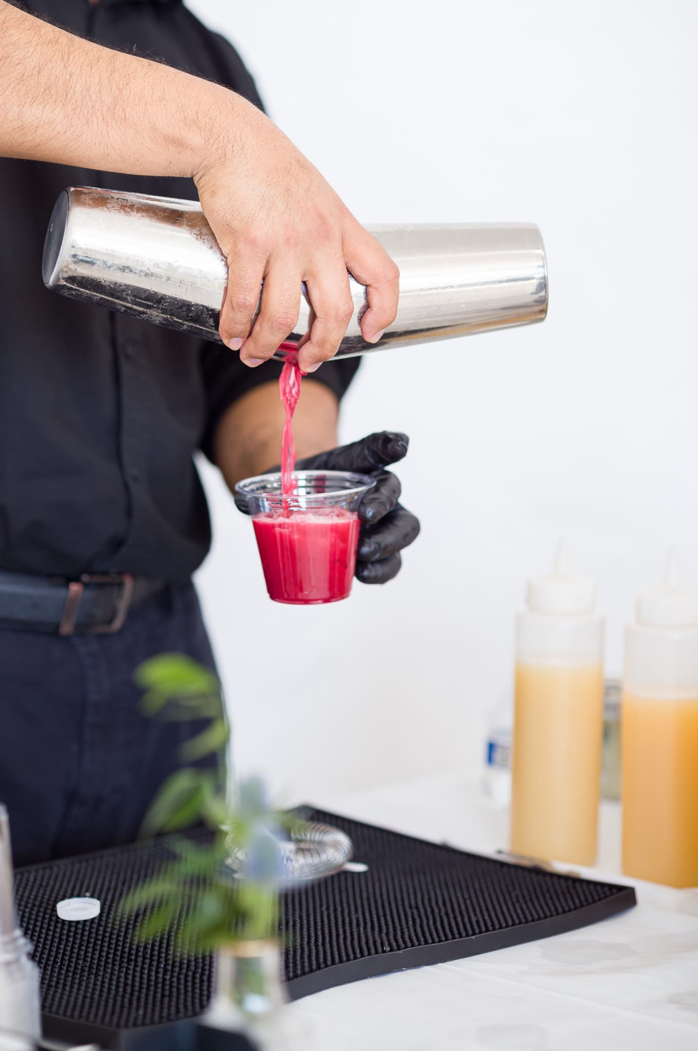 A vibrant red cocktail being poured into a cup at the bar