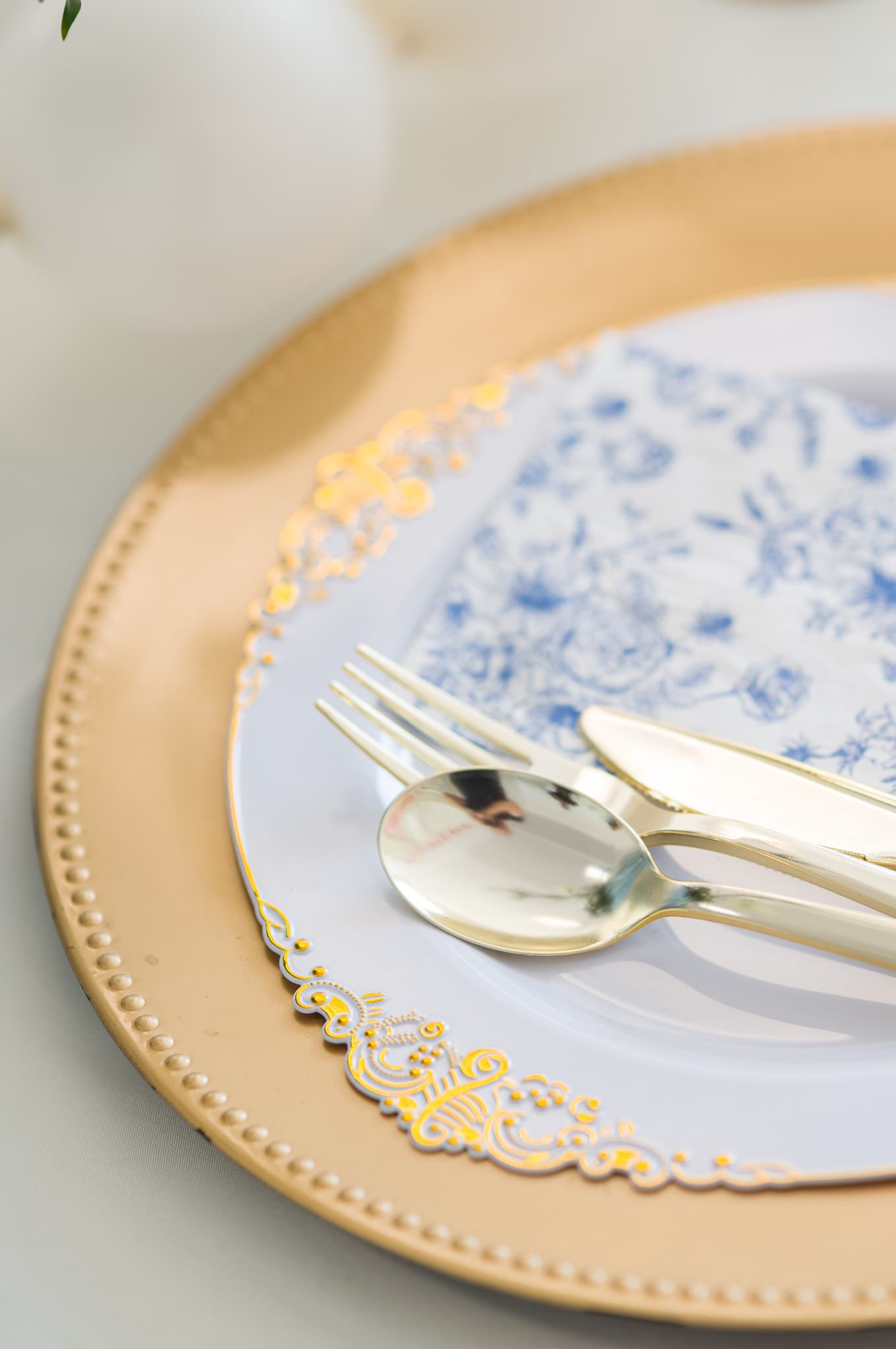 Gold charger plate with blue floral napkin and gold cutlery