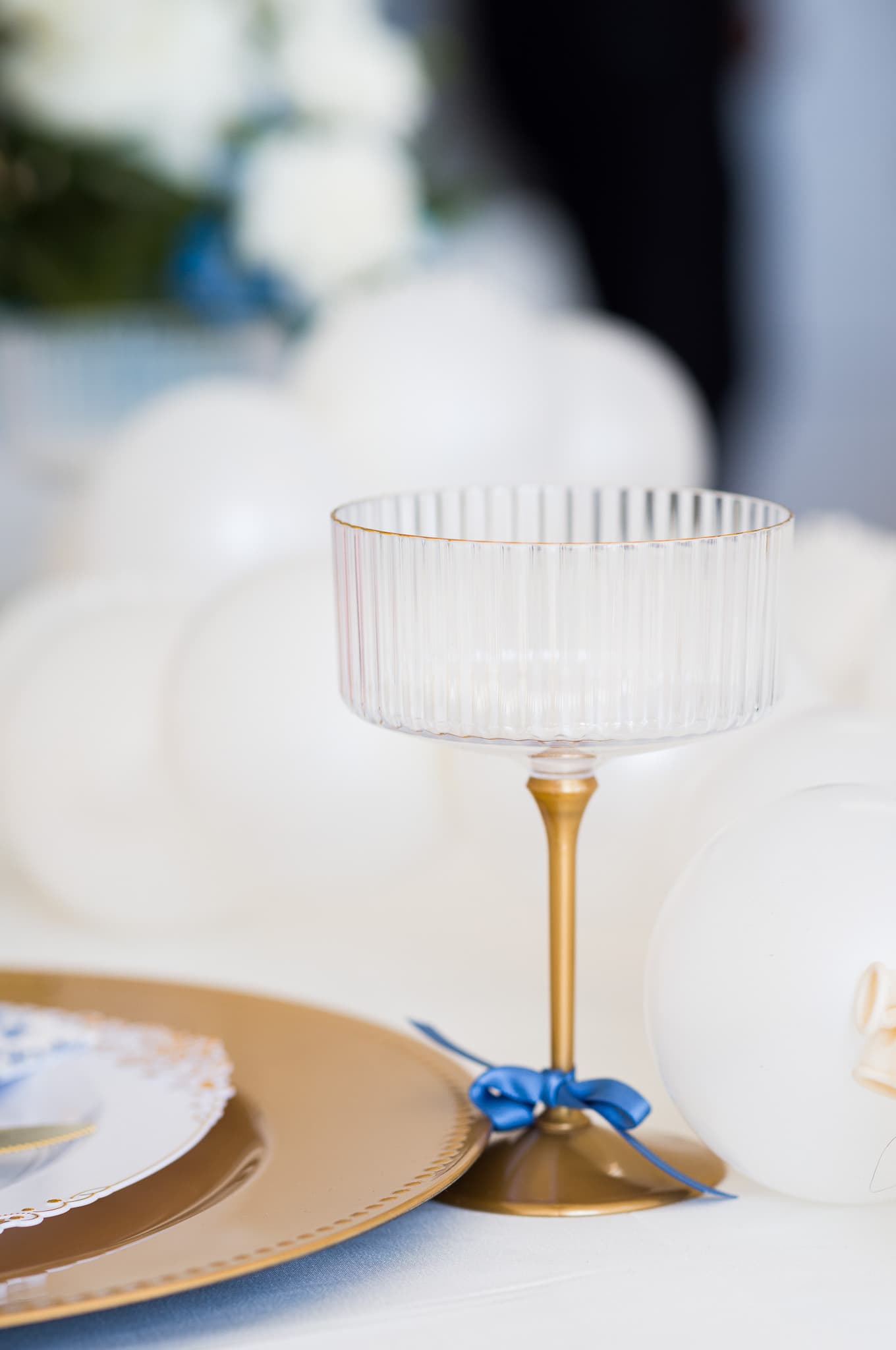 Ribbed coupe glass with a blue satin bow on the gold-rimmed stem