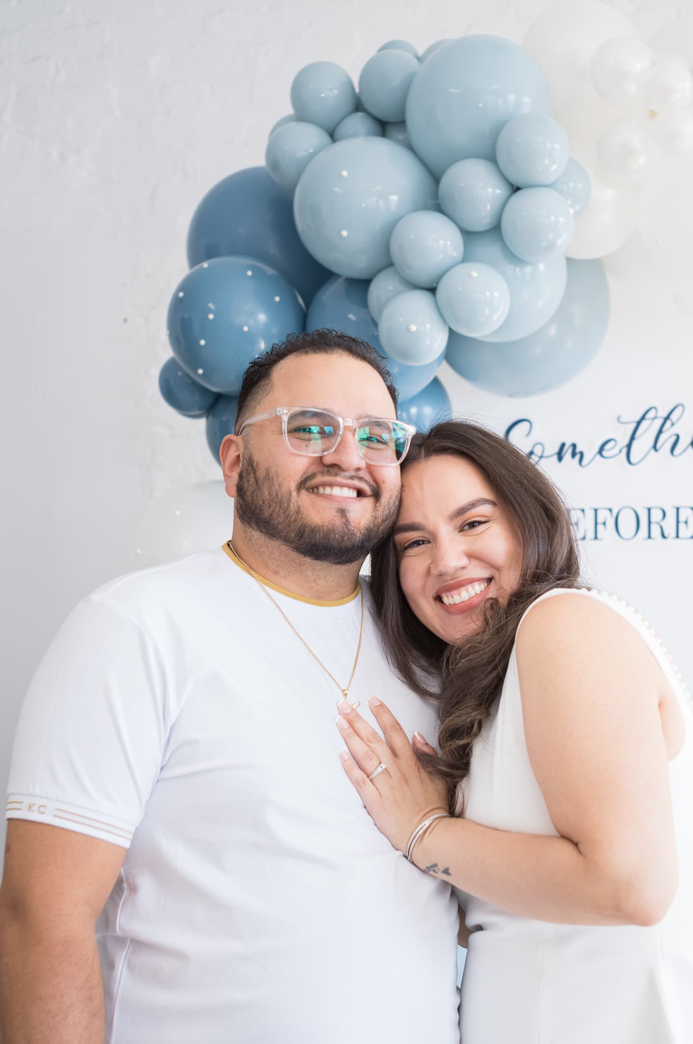 Jinet and John smiling together in front of the balloon backdrop