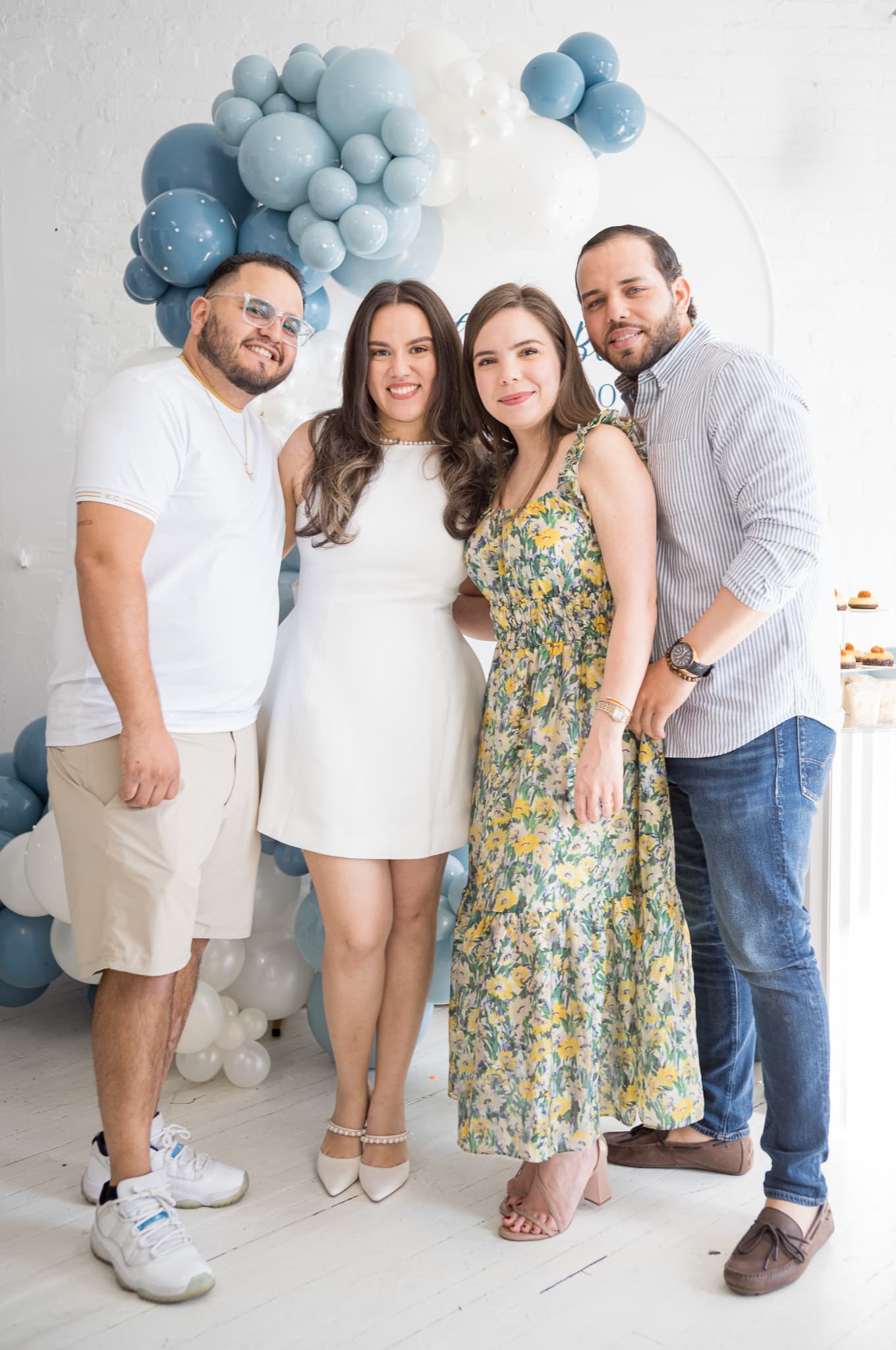 A group of four friends posing naturally under the balloon arch