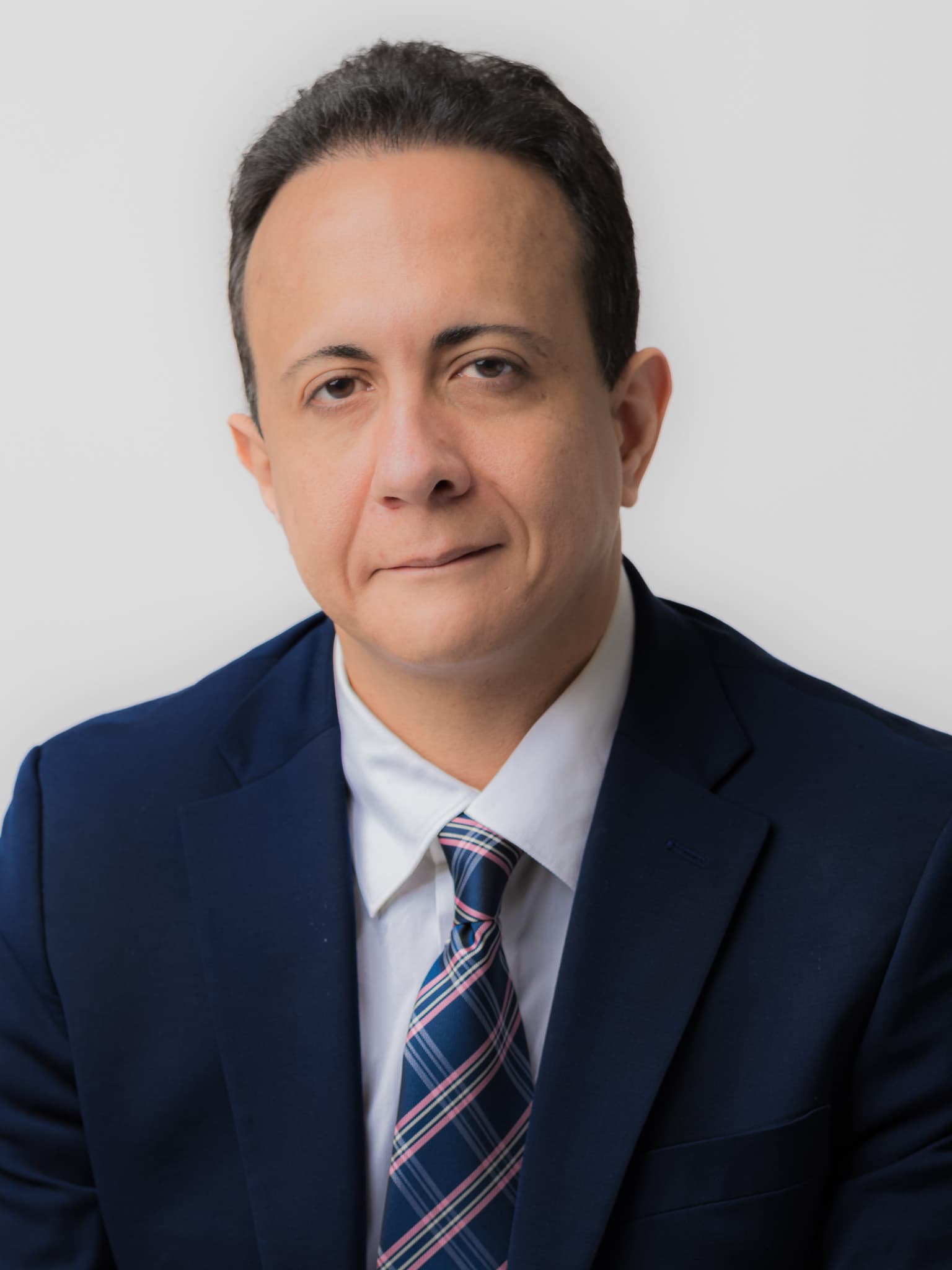 Man in a navy suit and striped tie, business headshot on a white background by Fuentes Studio