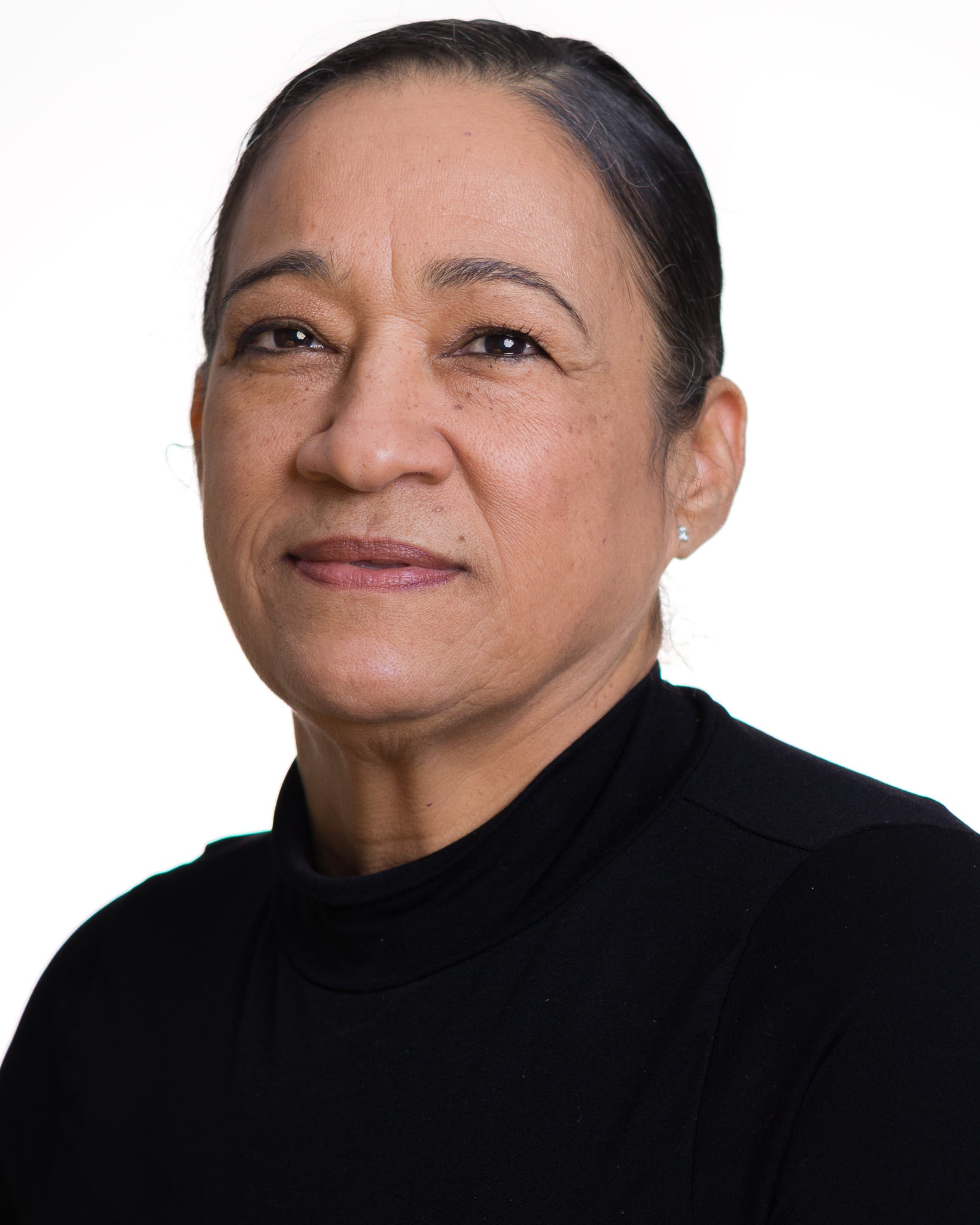Woman with dark hair pulled back in a black turtleneck, headshot on a white background by Fuentes Studio